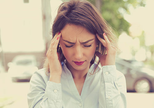 Woman holding head and closing her eyes